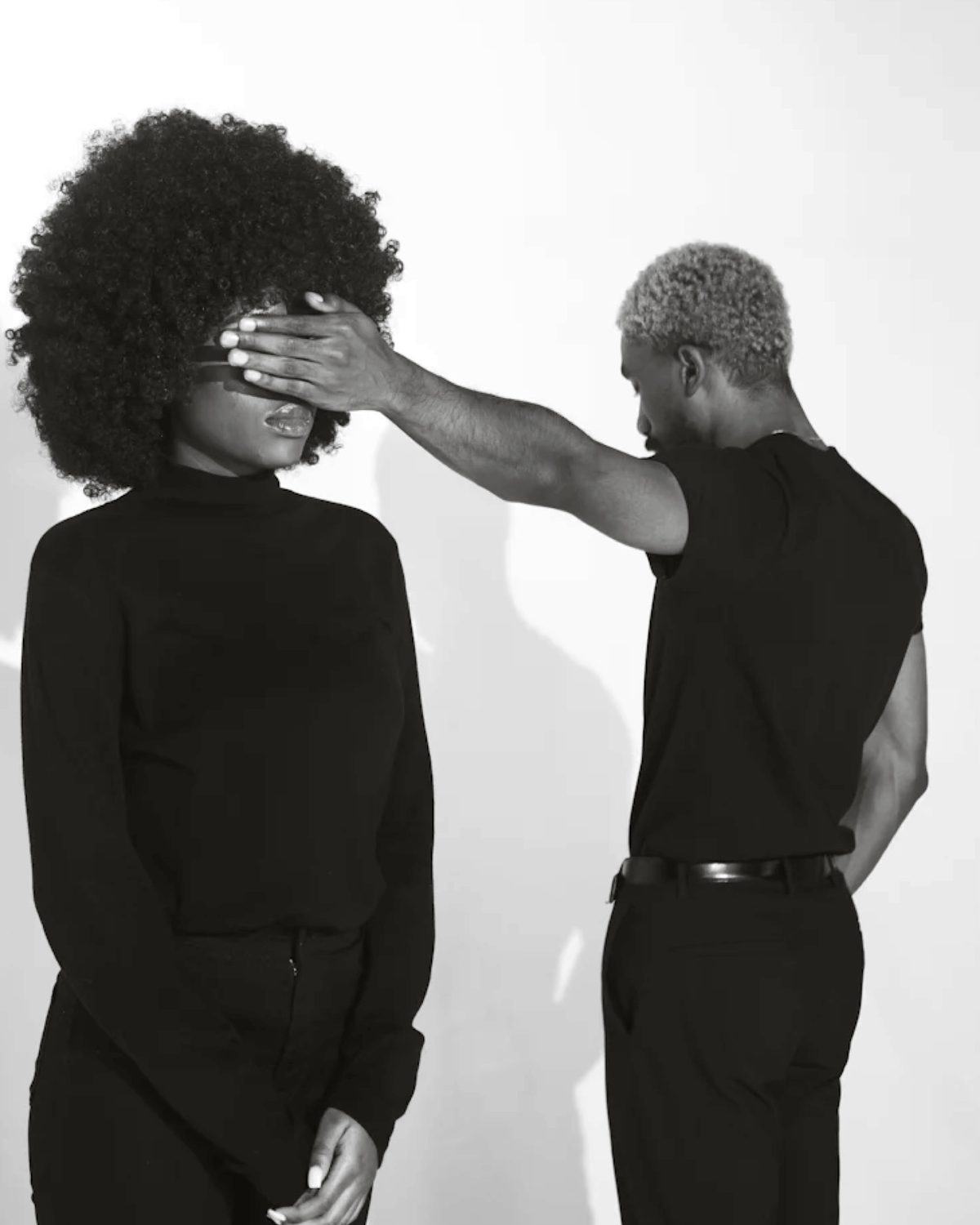 One person covering another person's eyes, black and white studio photograph
